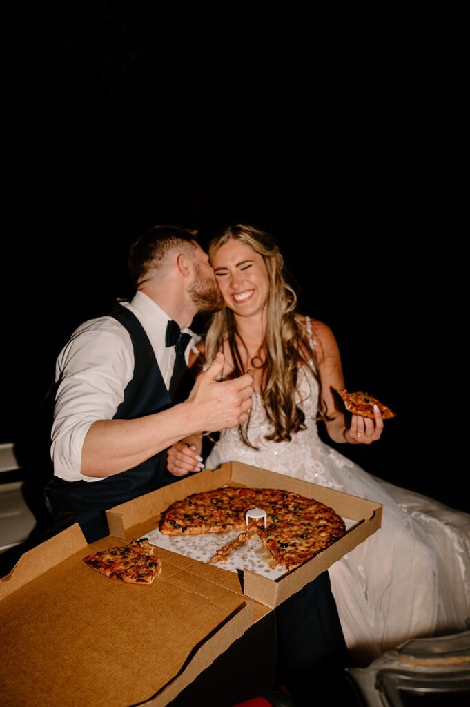 Bridal couple eating pizza as late night bit after wedding reception Photo by Indigo Lace