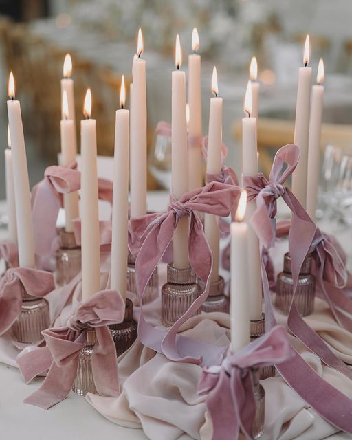 Bows tied around lit candles for wedding reception table Photo by Kamila Nowak
